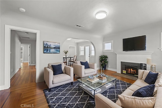 12950 7th St, Chino, CA 91710 - living area with arched walkways, wood finished floors, and a warm lit fireplace