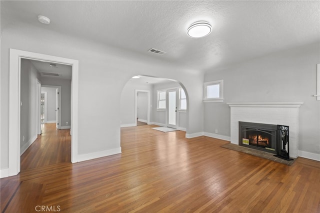 12950 7th St, Chino, CA 91710 - unfurnished living room featuring arched walkways, wood finished floors, a textured ceiling, and a fireplace