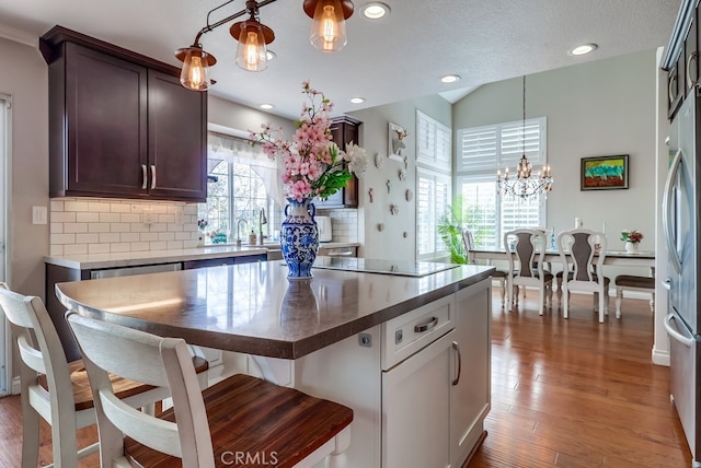 24813 Sagecrest Cir, Stevenson Ranch, CA 91381 - kitchen featuring black electric stovetop, stainless steel fridge, decorative backsplash, a chandelier, and wood finished floors