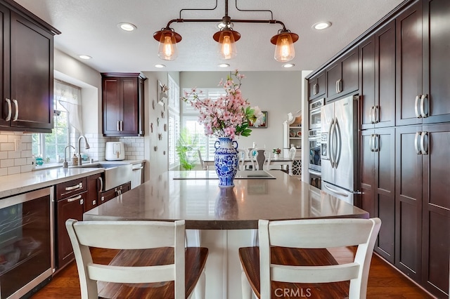 24813 Sagecrest Cir, Stevenson Ranch, CA 91381 - kitchen featuring wine cooler, appliances with stainless steel finishes, backsplash, a kitchen island, and dark brown cabinets