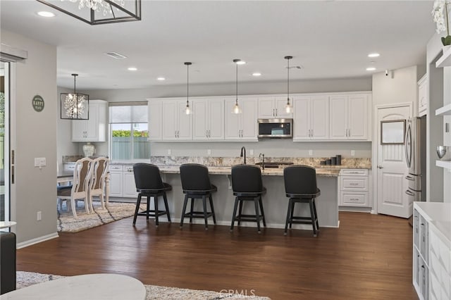 531 Owens River Dr, Oxnard, CA 93036 - kitchen with stainless steel appliances, recessed lighting, white cabinetry, dark wood-type flooring, and a center island with sink