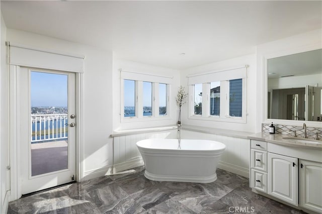 57 Cape Andover, Newport Beach, CA 92660 - full bathroom with marble tiled flooring, a soaking tub, vanity, wainscoting, and tasteful backsplash