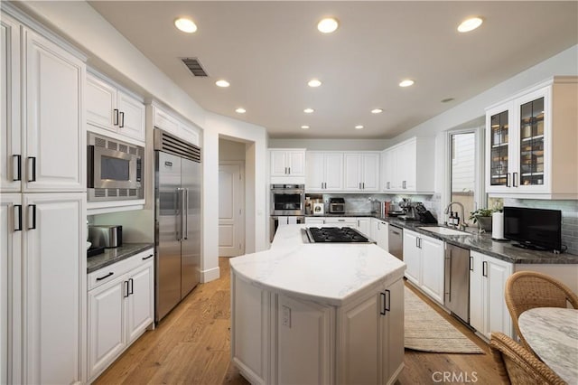 57 Cape Andover, Newport Beach, CA 92660 - kitchen featuring built in appliances, backsplash, a center island, white cabinets, and recessed lighting