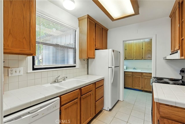 4041 57th St, Sacramento, CA 95820 - kitchen featuring white appliances, under cabinet range hood, light tile patterned flooring, tasteful backsplash, and brown cabinets