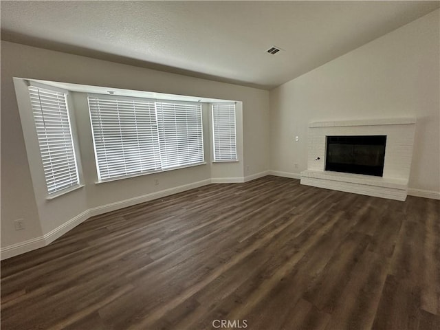 899 La Jolla Way, Merced, CA 95348 - unfurnished living room featuring dark wood-type flooring, a fireplace, vaulted ceiling, and plenty of natural light