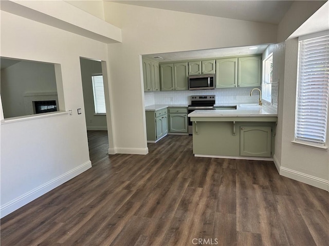 899 La Jolla Way, Merced, CA 95348 - kitchen with green cabinets, appliances with stainless steel finishes, light countertops, a peninsula, and backsplash