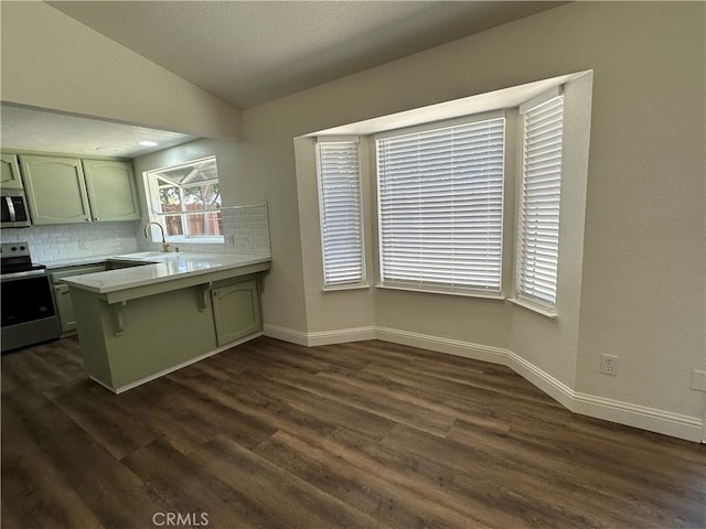 899 La Jolla Way, Merced, CA 95348 - kitchen with stainless steel appliances, a peninsula, backsplash, light countertops, and dark wood finished floors