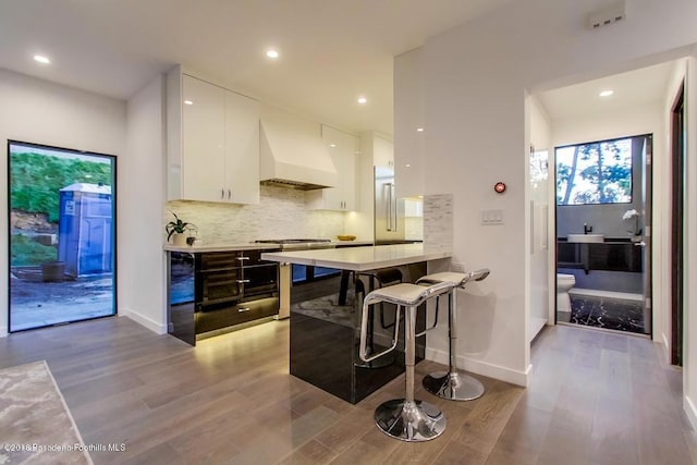 940 Burleigh Dr, Pasadena, CA 91105 - kitchen with custom exhaust hood, white cabinets, a breakfast bar area, light wood-style floors, and modern cabinets