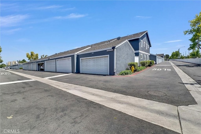 195 Morristown Ln, Costa Mesa, CA 92626 - view of property exterior featuring community garages, stucco siding, and roof with shingles