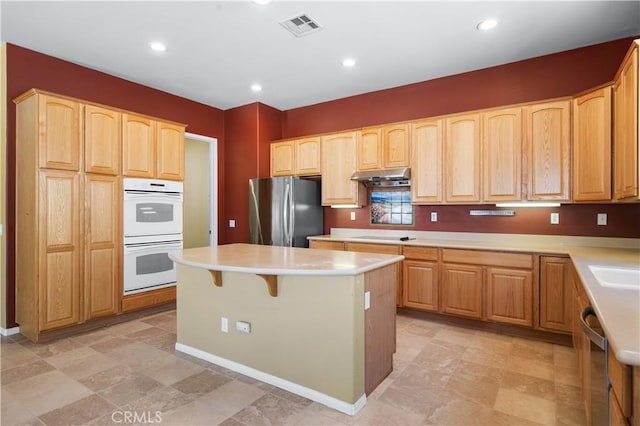 1706 Brittney Rd, Beaumont, CA 92223 - kitchen with stainless steel appliances, under cabinet range hood, light brown cabinetry, a center island, and recessed lighting