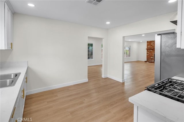 12815 Rexton St, Norwalk, CA 90650 - kitchen with freestanding refrigerator, white cabinetry, light wood finished floors, recessed lighting, and light stone counters