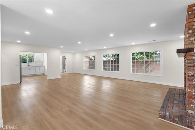 12815 Rexton St, Norwalk, CA 90650 - unfurnished living room featuring light wood-style flooring, recessed lighting, and a brick fireplace
