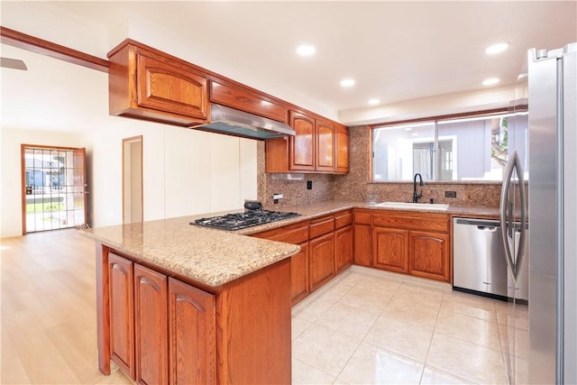 12711 Leroy Ave, Garden Grove, CA 92841 - kitchen with appliances with stainless steel finishes, a peninsula, brown cabinets, backsplash, and light stone counters