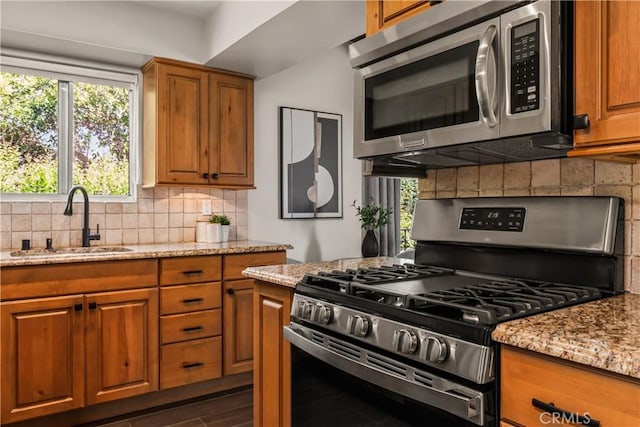 4230 Whitsett Ave Unit 6, Studio City, CA 91604 - kitchen featuring appliances with stainless steel finishes, brown cabinets, light stone countertops, tasteful backsplash, and plenty of natural light