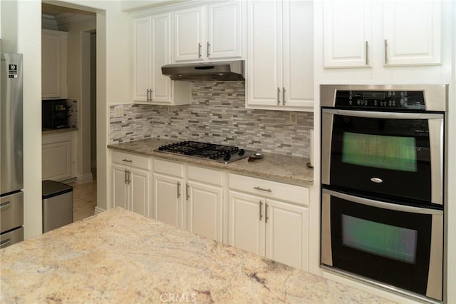 2417 Lenai Cir, Corona, CA 92879 - kitchen with appliances with stainless steel finishes, under cabinet range hood, white cabinetry, tasteful backsplash, and light stone counters