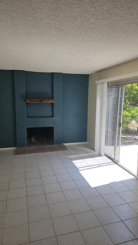 4028 Johnson Dr, Oceanside, CA 92056 - tiled spare room featuring a large fireplace and a textured ceiling