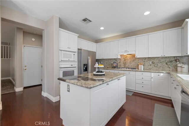 30336 Barcelona Rd, Castaic, CA 91384 - kitchen with appliances with stainless steel finishes, a center island, white cabinets, decorative backsplash, and under cabinet range hood