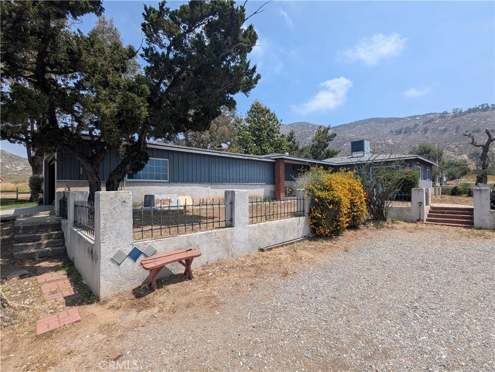8974 Pigeon Pass Rd, Moreno Valley, CA 92557 - view of front of house with a fenced front yard, a mountain view, and board and batten siding