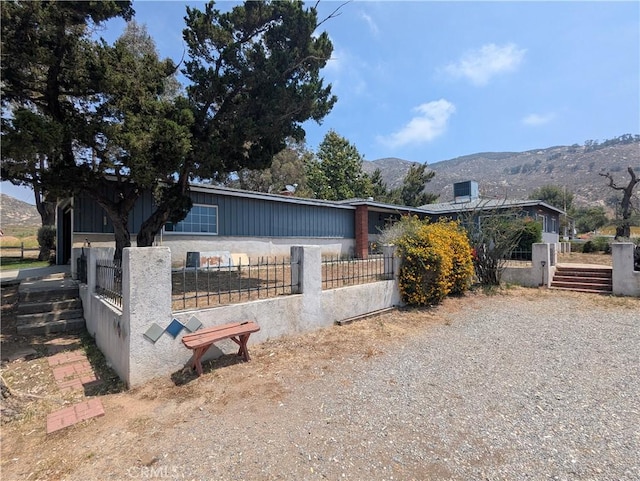 8974 Pigeon Pass Rd, Moreno Valley, CA 92557 - view of front of house with a fenced front yard, a mountain view, and board and batten siding
