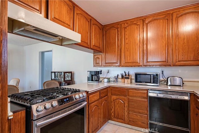 10415 Valley View Ave, Whittier, CA 90604 - kitchen with appliances with stainless steel finishes, under cabinet range hood, brown cabinets, light countertops, and a peninsula