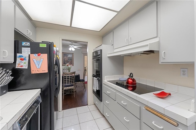 3500 W Manchester Blvd Unit 240, Inglewood, CA 90305 - kitchen with black appliances, tile countertops, under cabinet range hood, light tile patterned floors, and a ceiling fan