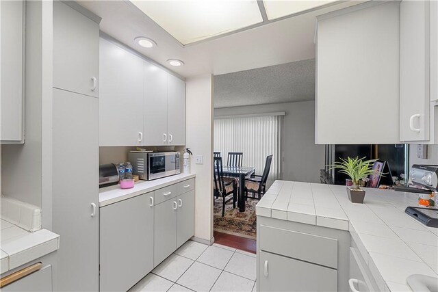 3500 W Manchester Blvd Unit 240, Inglewood, CA 90305 - kitchen featuring stainless steel microwave, light tile patterned floors, tile counters, recessed lighting, and white cabinets