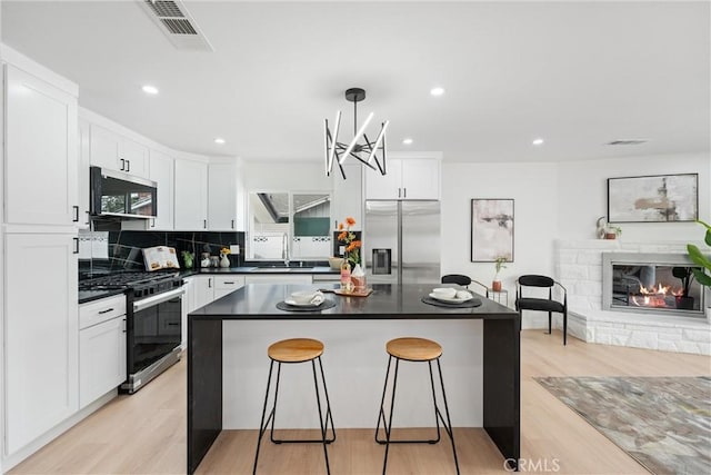 8771 La Grand Ave, Garden Grove, CA 92841 - kitchen with stainless steel appliances, a breakfast bar area, dark countertops, white cabinetry, and recessed lighting