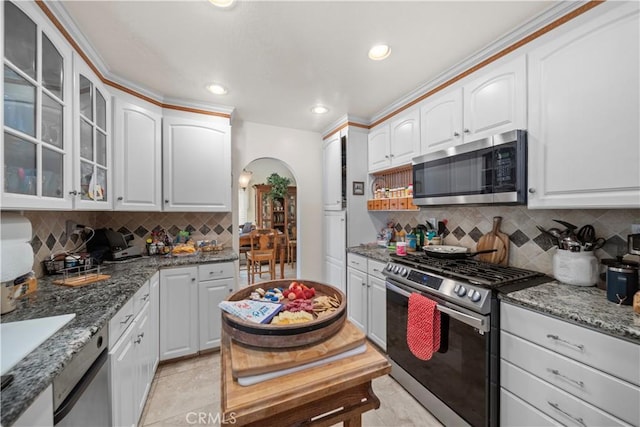 1142 Daisy Cir, Corona, CA 92882 - kitchen featuring stainless steel appliances, arched walkways, glass insert cabinets, stone countertops, and tasteful backsplash