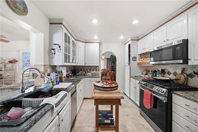 1142 Daisy Cir, Corona, CA 92882 - kitchen with appliances with stainless steel finishes, arched walkways, backsplash, glass insert cabinets, and white cabinetry