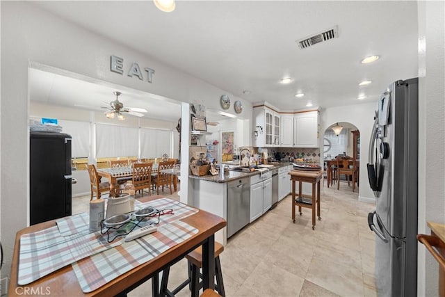 1142 Daisy Cir, Corona, CA 92882 - kitchen featuring stainless steel appliances, arched walkways, ceiling fan, white cabinetry, and glass insert cabinets
