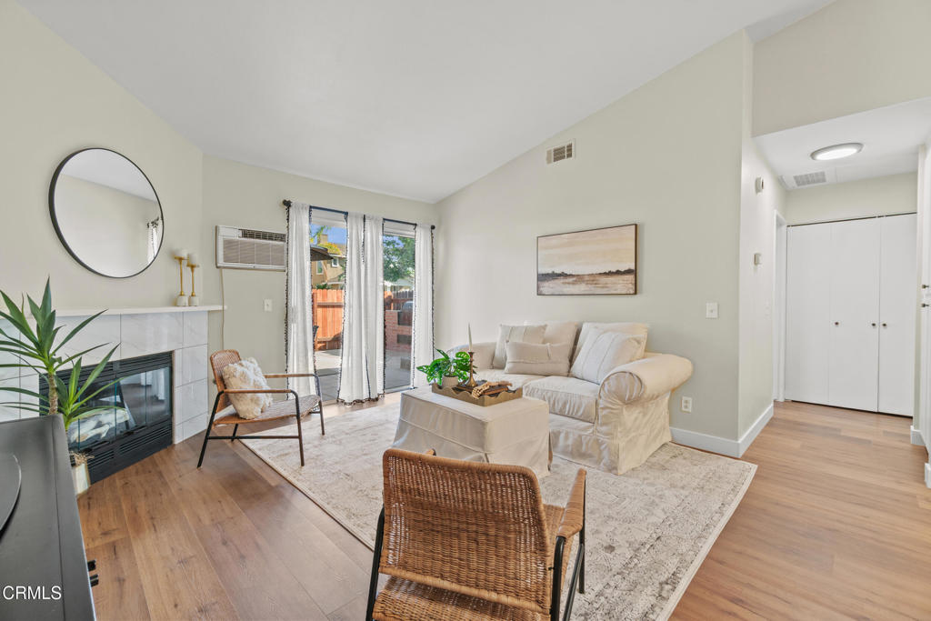 107 B St, Fillmore, CA 93015 - living room with a wall mounted AC, wood finished floors, a tile fireplace, and lofted ceiling
