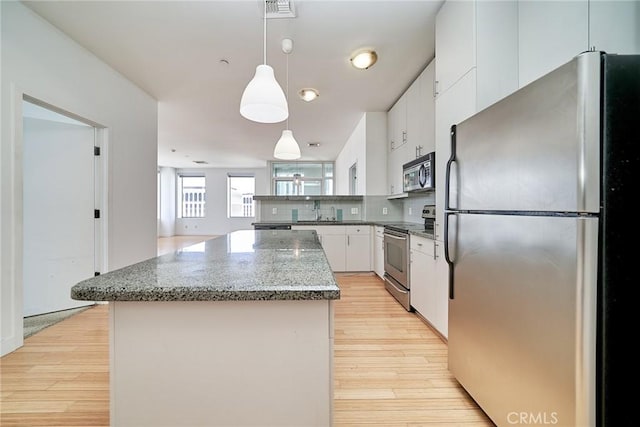 3810 Wilshire Blvd Unit 805, Los Angeles, CA 90010 - kitchen with stainless steel appliances, a center island, light wood-type flooring, white cabinets, and decorative backsplash