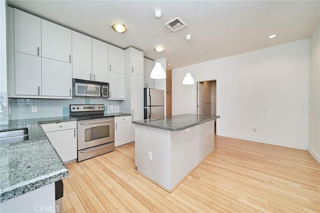 3810 Wilshire Blvd Unit 805, Los Angeles, CA 90010 - kitchen featuring appliances with stainless steel finishes, light wood-type flooring, tasteful backsplash, a center island, and hanging light fixtures