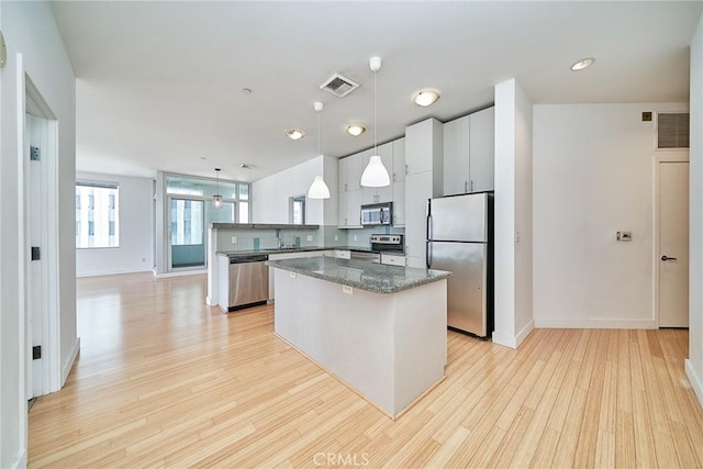 3810 Wilshire Blvd Unit 805, Los Angeles, CA 90010 - kitchen with appliances with stainless steel finishes, a kitchen island, light wood-style flooring, hanging light fixtures, and a peninsula