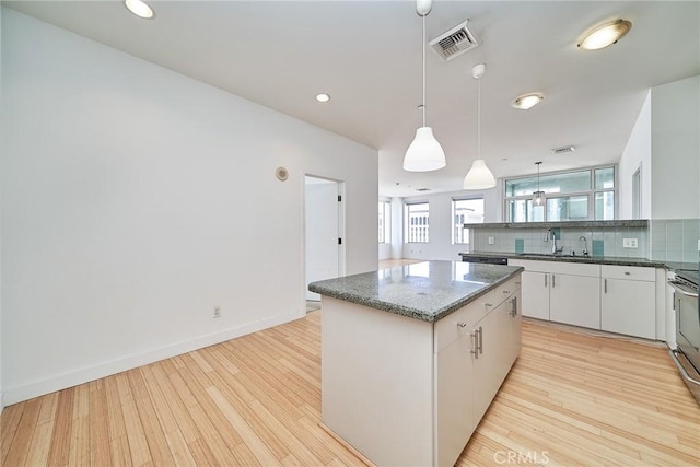 3810 Wilshire Blvd Unit 805, Los Angeles, CA 90010 - kitchen featuring decorative backsplash, light wood-style floors, a center island, white cabinets, and decorative light fixtures