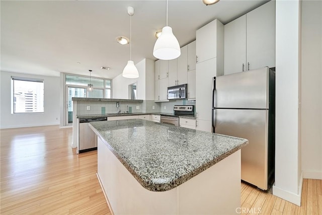 3810 Wilshire Blvd Unit 805, Los Angeles, CA 90010 - kitchen with appliances with stainless steel finishes, tasteful backsplash, light wood-style floors, a center island, and decorative light fixtures
