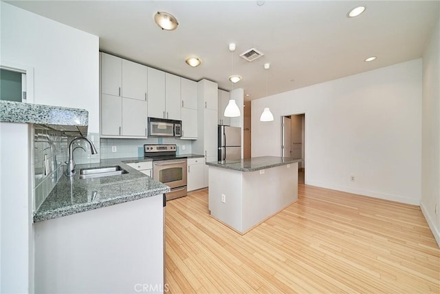 3810 Wilshire Blvd Unit 805, Los Angeles, CA 90010 - kitchen featuring appliances with stainless steel finishes, a kitchen island, light wood-style flooring, decorative light fixtures, and backsplash