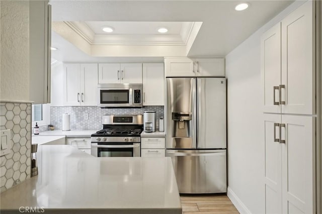 306 San Nicholas Ct, Laguna Beach, CA 92651 - kitchen featuring appliances with stainless steel finishes, crown molding, a raised ceiling, white cabinets, and light countertops