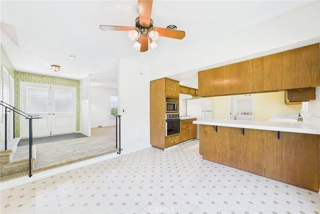 10469 Gregory Cir, Cypress, CA 90630 - kitchen with oven, brown cabinetry, light flooring, stainless steel microwave, and a peninsula