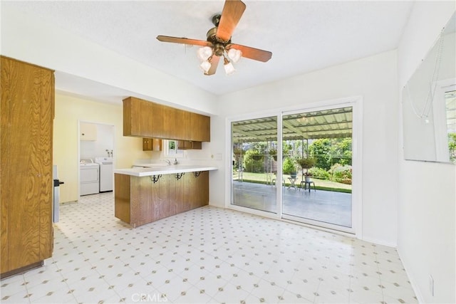 10469 Gregory Cir, Cypress, CA 90630 - kitchen featuring independent washer and dryer, brown cabinetry, light flooring, a peninsula, and light countertops