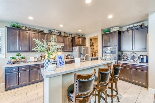 14655 Spanish Bay Way, Chowchilla, CA 93610 - kitchen with stainless steel appliances, light countertops, dark brown cabinets, a kitchen bar, and recessed lighting