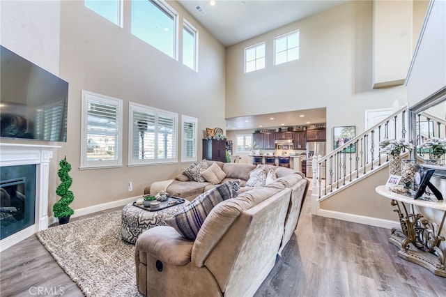 14655 Spanish Bay Way, Chowchilla, CA 93610 - living room featuring light wood finished floors, a high ceiling, a glass covered fireplace, and stairway