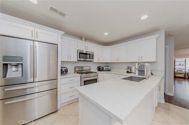 9724 Walker Ct Unit 18, Cypress, CA 90630 - kitchen featuring appliances with stainless steel finishes, a peninsula, white cabinets, light countertops, and recessed lighting
