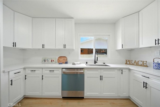 1113 W 78th St, Los Angeles, CA 90044 - kitchen featuring stainless steel dishwasher, white cabinets, light countertops, light wood-style floors, and tasteful backsplash