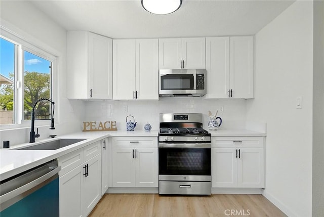 1113 W 78th St, Los Angeles, CA 90044 - kitchen featuring appliances with stainless steel finishes, light wood-type flooring, tasteful backsplash, light countertops, and white cabinets