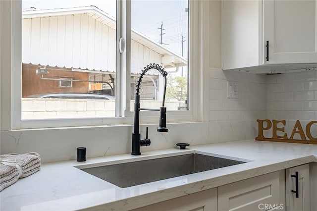 1113 W 78th St, Los Angeles, CA 90044 - kitchen with decorative backsplash, white cabinetry, and light stone counters
