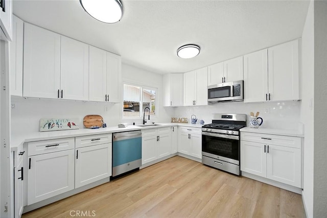 1113 W 78th St, Los Angeles, CA 90044 - kitchen with appliances with stainless steel finishes, light wood-style flooring, light countertops, and white cabinets