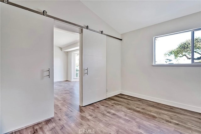 6470 Flamingo Dr, Buena Park, CA 90620 - empty room featuring a barn door, vaulted ceiling, and light wood-type flooring