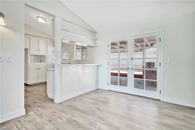 6470 Flamingo Dr, Buena Park, CA 90620 - kitchen with french doors, light countertops, light wood-style flooring, white cabinetry, and vaulted ceiling