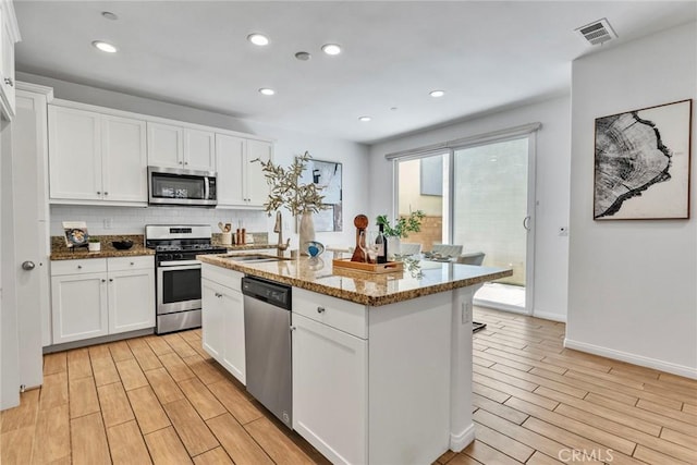 10578 Wells Dr, Rancho Cucamonga, CA 91730 - kitchen with appliances with stainless steel finishes, light wood-type flooring, light stone counters, backsplash, and white cabinetry